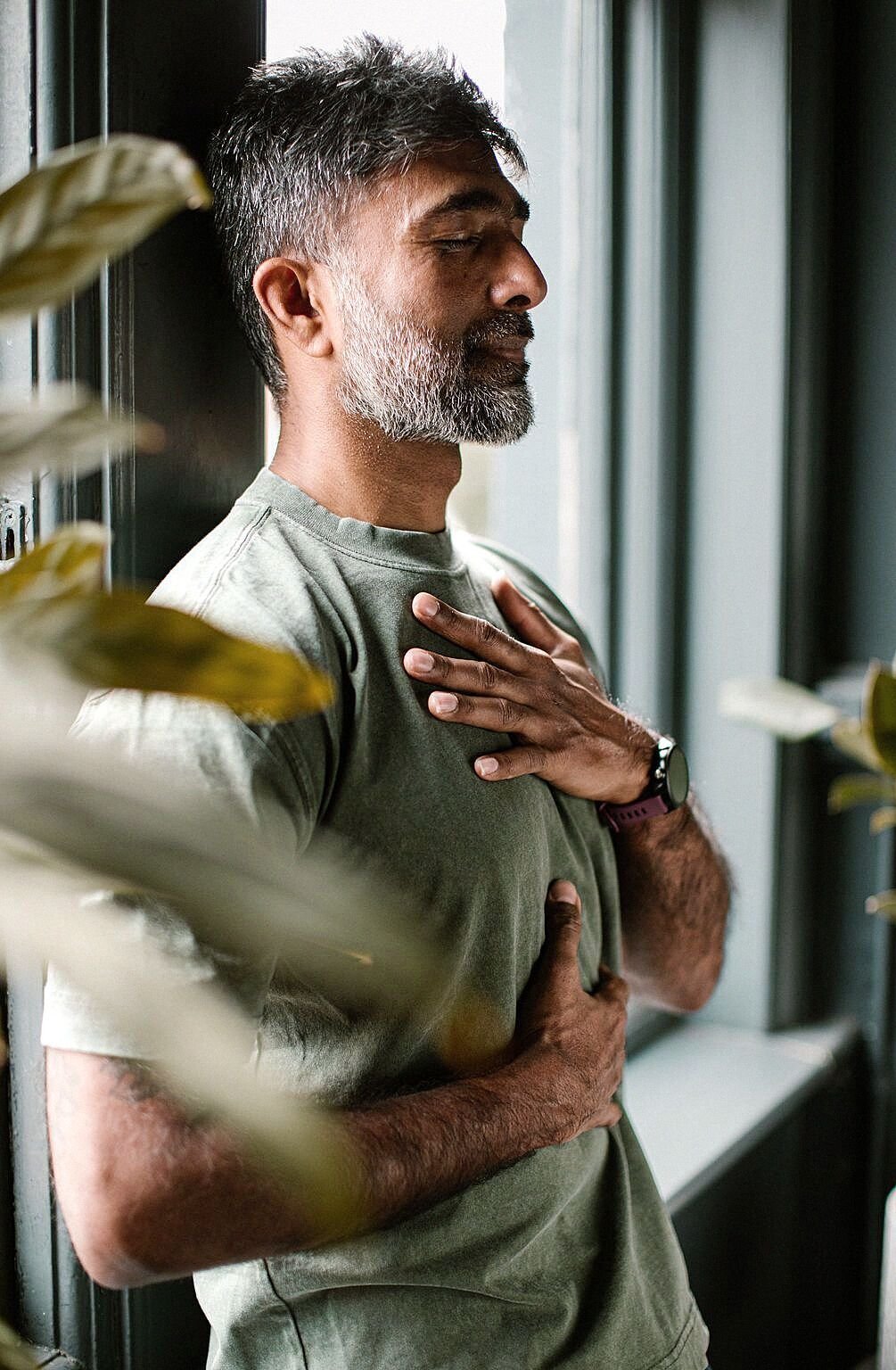 A man in a mindful moment of self-connection by a window